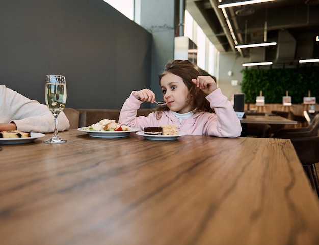 Hermosa niña caucásica comiendo un delicioso pastel en el restaurante del aeropuerto