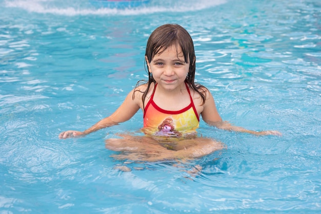 Hermosa niña caucásica en la piscina refrescante en verano