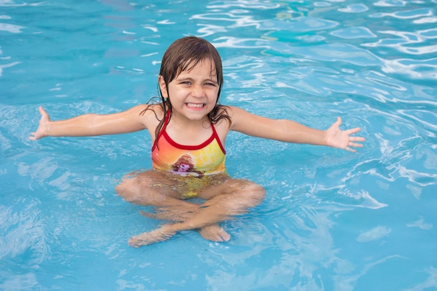 Hermosa niña caucásica en la piscina refrescante en verano