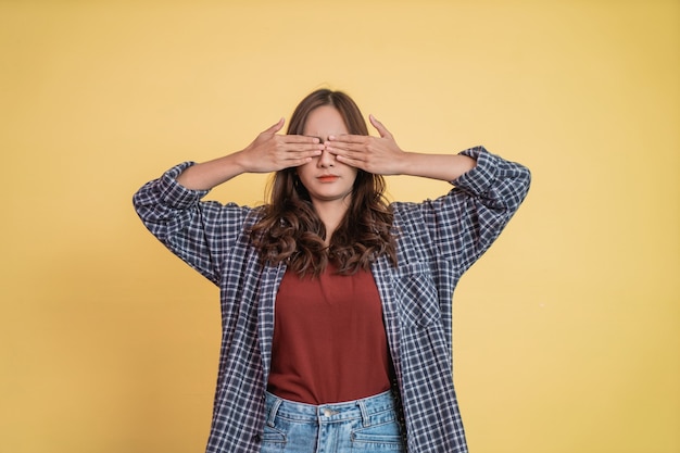 Una hermosa niña cierra los ojos con ambas manos.