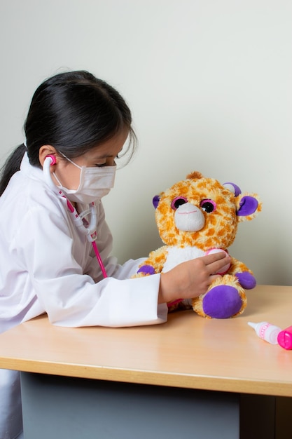 hermosa niña colombiana juega a un médico pediatra examinando sus juguetes