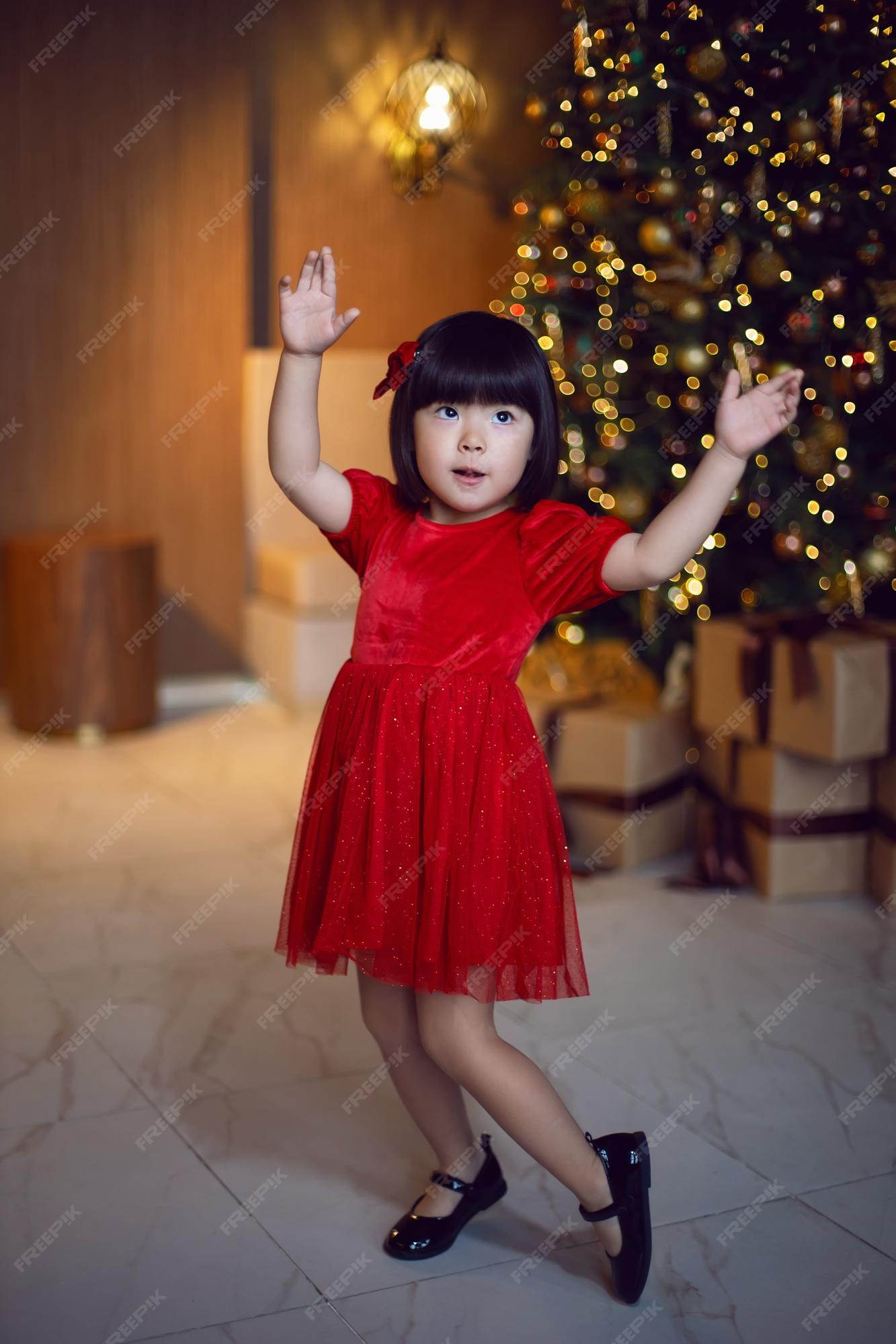 niña coreana en rojo se en el árbol de navidad el día de navidad | Premium