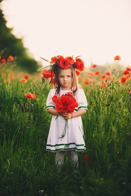 Hermosa niña con una corona de amapolas en la cabeza.