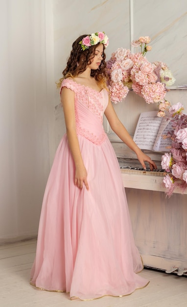 Foto una hermosa niña con una corona de flores en la cabeza y un vestido largo rosa es fotografiada en un estudio fotográfico spring photosession