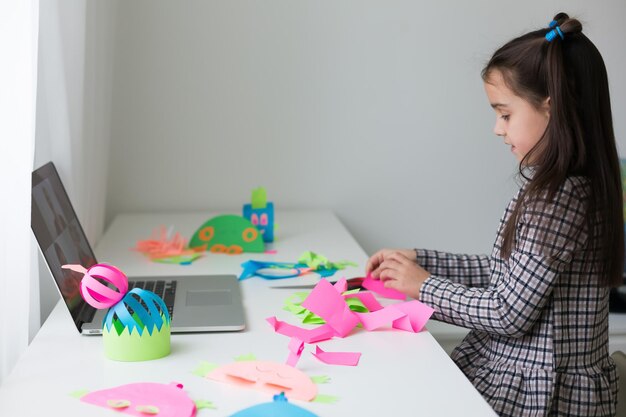 Hermosa niña cortando papel con tijeras en la clase de lección de arte. Concepto de educación infantil. Manualidades para niños. De regreso a la escuela.