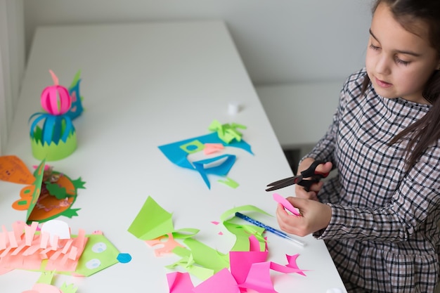 Hermosa niña cortando papel con tijeras en la clase de lección de arte. Concepto de educación infantil. Manualidades para niños. De regreso a la escuela.