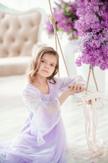 Hermosa niña en un delicado vestido con flores de color lila