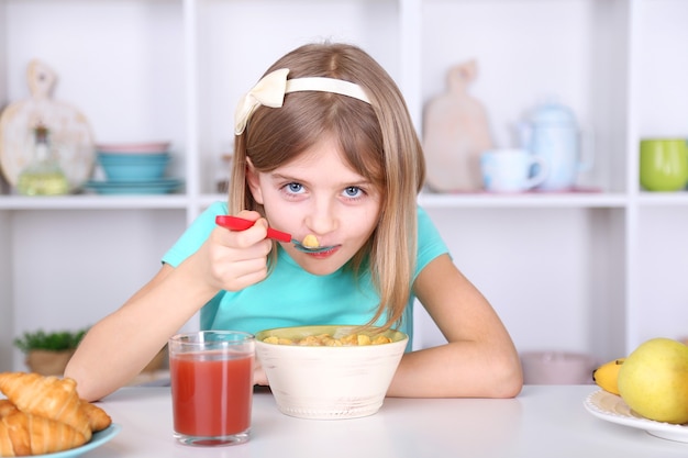 Hermosa niña desayunando en la cocina de casa