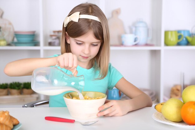 Hermosa niña desayunando en la cocina de casa