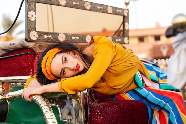 Una hermosa niña descansa en un carruaje en la plaza Jemaa el-Fna. Marrakech, Marruecos