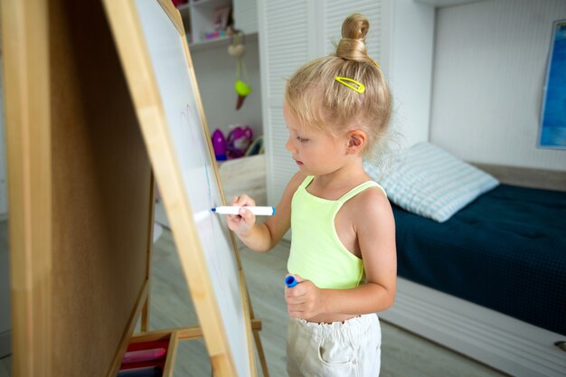 hermosa niña dibuja en la pizarra en casa