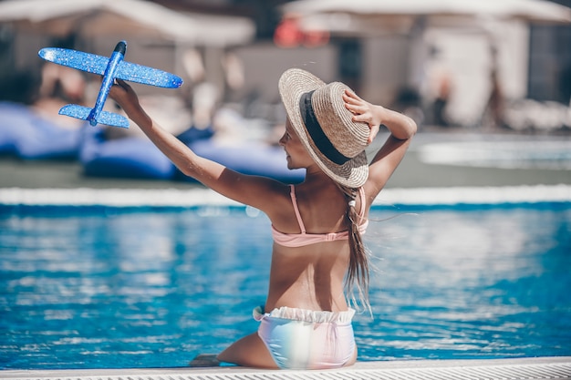 Hermosa niña divirtiéndose cerca de una piscina al aire libre