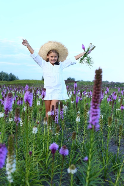 hermosa niña dos manos arriba en un campo de flores