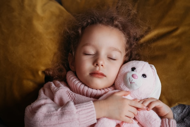 Hermosa niña duerme con un peluche