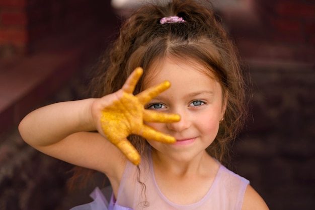 Una hermosa niña encantadora con ojos azules claros muestra cinco dedos en su mano