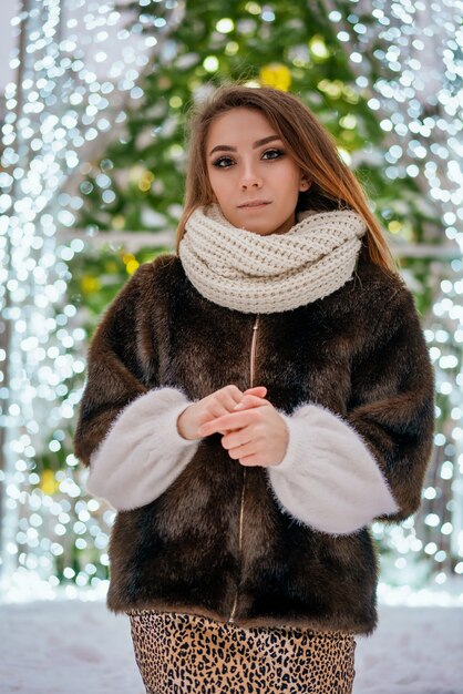 Una hermosa niña se encuentra en el fondo del árbol de Navidad de la ciudad