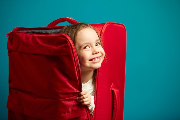 Hermosa niña escondida en una maleta para vacaciones