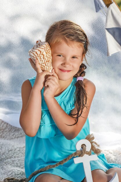 Hermosa niña escucha el mar a través de la concha