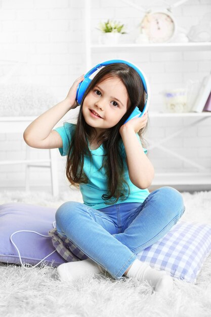 Foto hermosa niña escuchando música en la habitación