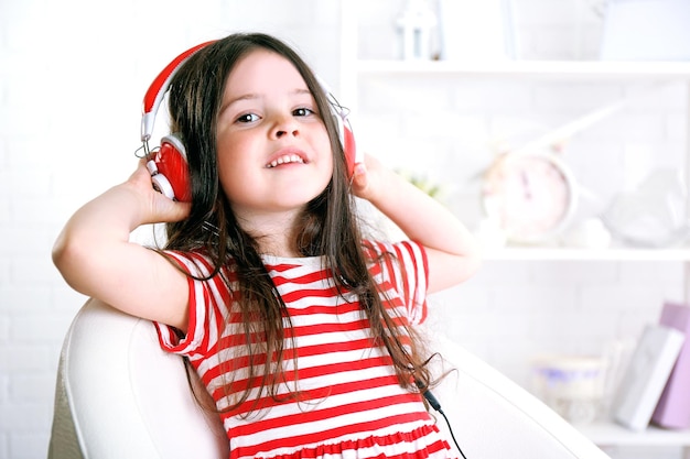 Hermosa niña escuchando música en la habitación