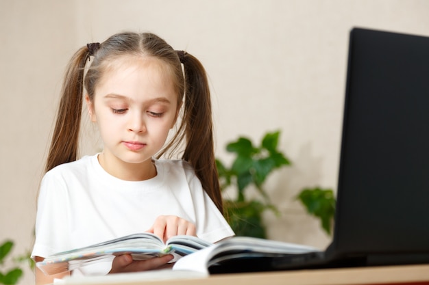 Hermosa niña de la escuela que trabaja en casa en su habitación con un portátil y notas de clase estudiando en un