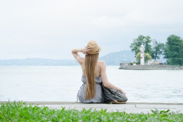 Hermosa niña está sentada en el muelle