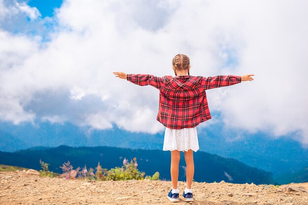 Foto hermosa niña feliz en las montañas en el fondo de niebla