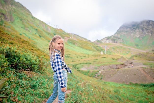 Hermosa niña feliz en las montañas en el fondo de niebla