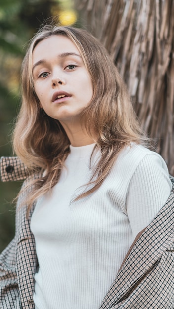 Hermosa niña feliz con el pelo largo, con ropa elegante, posando en la calle otoño.