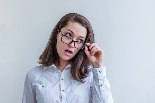 Hermosa niña feliz sonriendo. Belleza simple retrato joven sonriente mujer morena en las lentes aisladas en la pared blanca. Emoción humana positiva expresión facial lenguaje corporal. Copia espacio