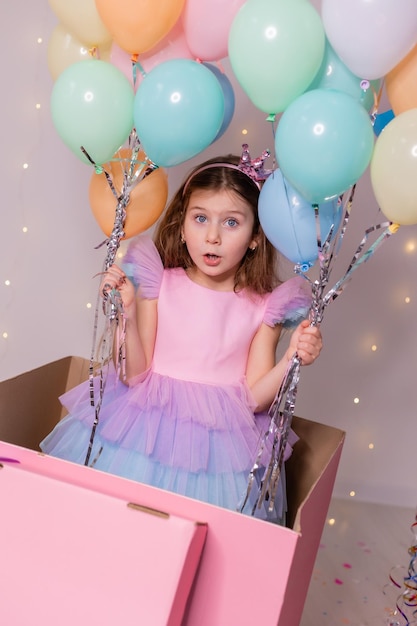 Hermosa niña con globos salta de una enorme caja rosa niño celebra su cumpleaños