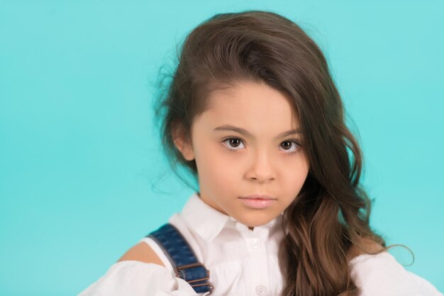 Hermosa niña con hermoso cabello sano usar blusa blanca Niña con cabello rizado sobre fondo azul