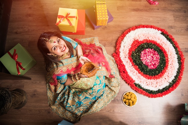 Hermosa niña india sosteniendo diya en la noche del festival de diwali, vista superior enfoque selectivo.