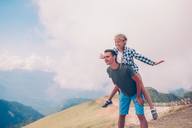 Hermosa niña y joven padre en las montañas en el fondo de niebla