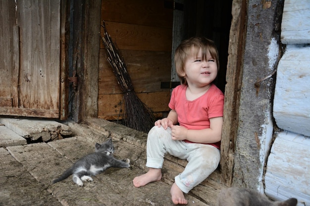 Una hermosa niña juega con un gato en el pueblo de mi abuela.