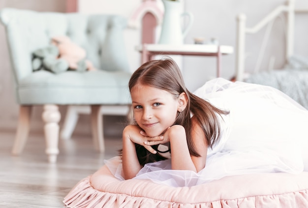 Hermosa niña juega en la sala de luz. Retrato de un niño feliz