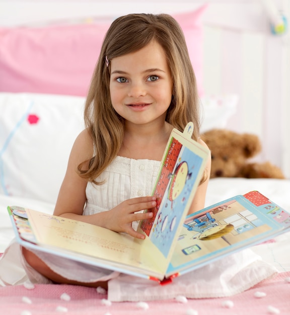 Foto hermosa niña leyendo en la cama