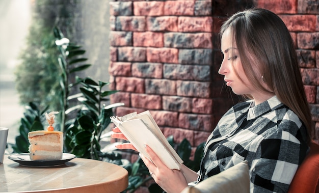 Hermosa niña leyendo un libro en un café