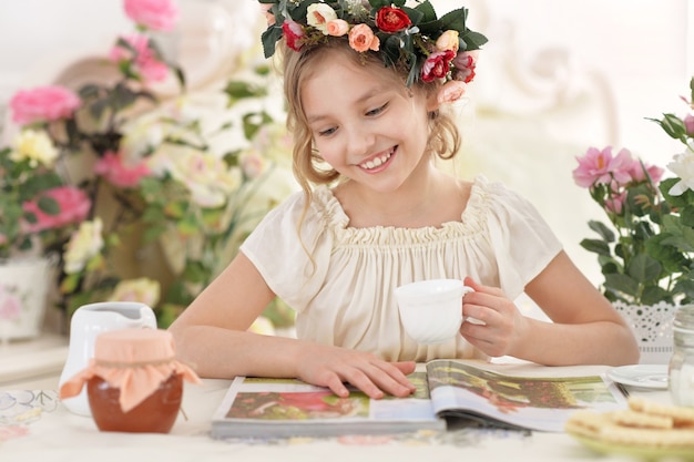 Hermosa niña leyendo una revista en casa