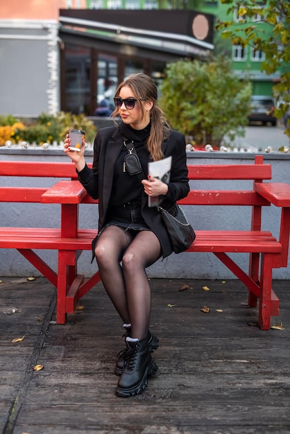 Hermosa niña linda bien arreglada disfruta de un café en su ciudad de otoño favorita. Concepto de otoño. Concepto de ciudad. El concepto de paseos por la ciudad