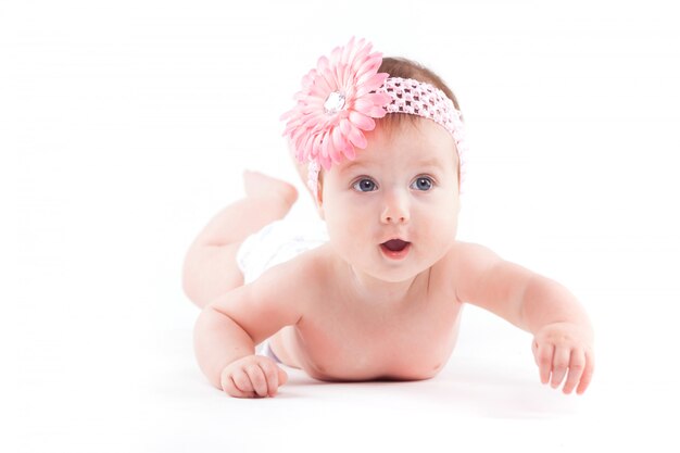 Hermosa niña linda en envoltura de flores de color rosa se encuentra boca abajo