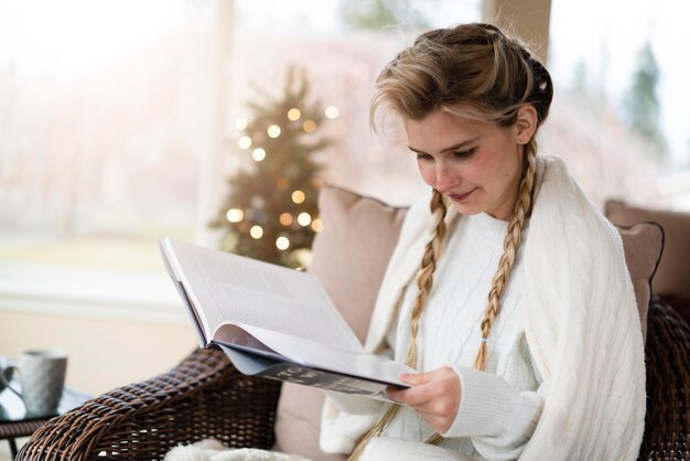 Una hermosa niña en una luminosa sala de Navidad lee un libro y bebe té