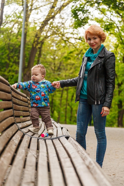 Hermosa niña madre con un hijo en el parque en el parque está sentada en un banco