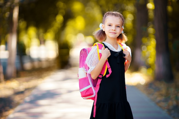 Hermosa niña con mochila caminando en el parque