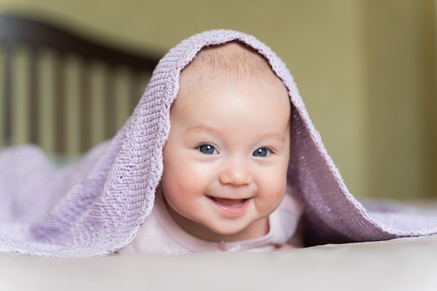 hermosa niña de ojos azules recién nacida se encuentra boca abajo y sonríe