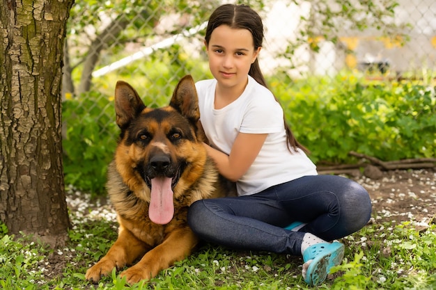 hermosa niña con un pastor alemán jugando en el césped durante el día.