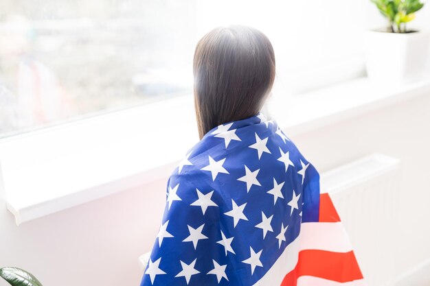 Hermosa niña patriótica con la bandera estadounidense en sus manos extendidas.