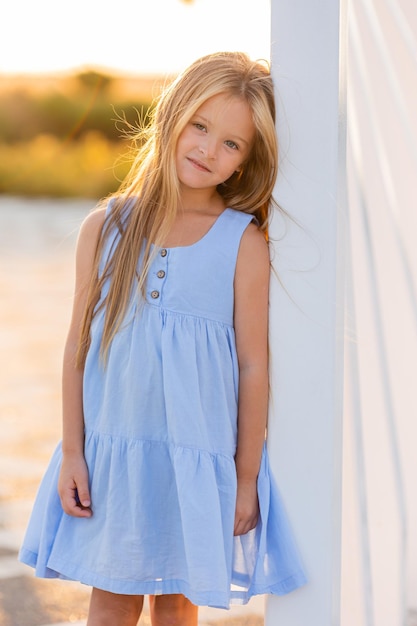 hermosa niña con el pelo largo y rubio camina al atardecer en el parque de la ciudad en verano