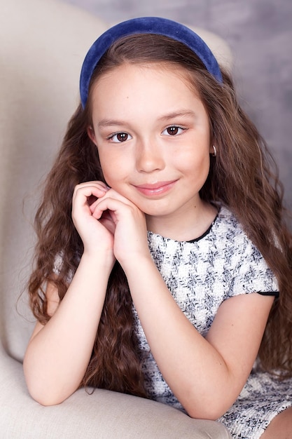 Hermosa niña con el pelo largo en un vestido de pie y posando sobre un fondo blanco en el estudio