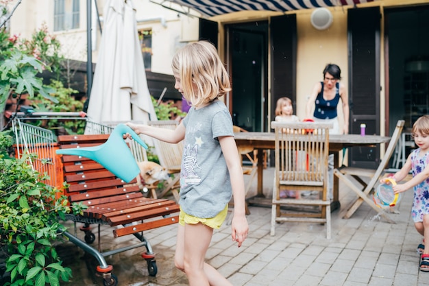 Hermosa niña pequeña en casa terraza jugando jardinería